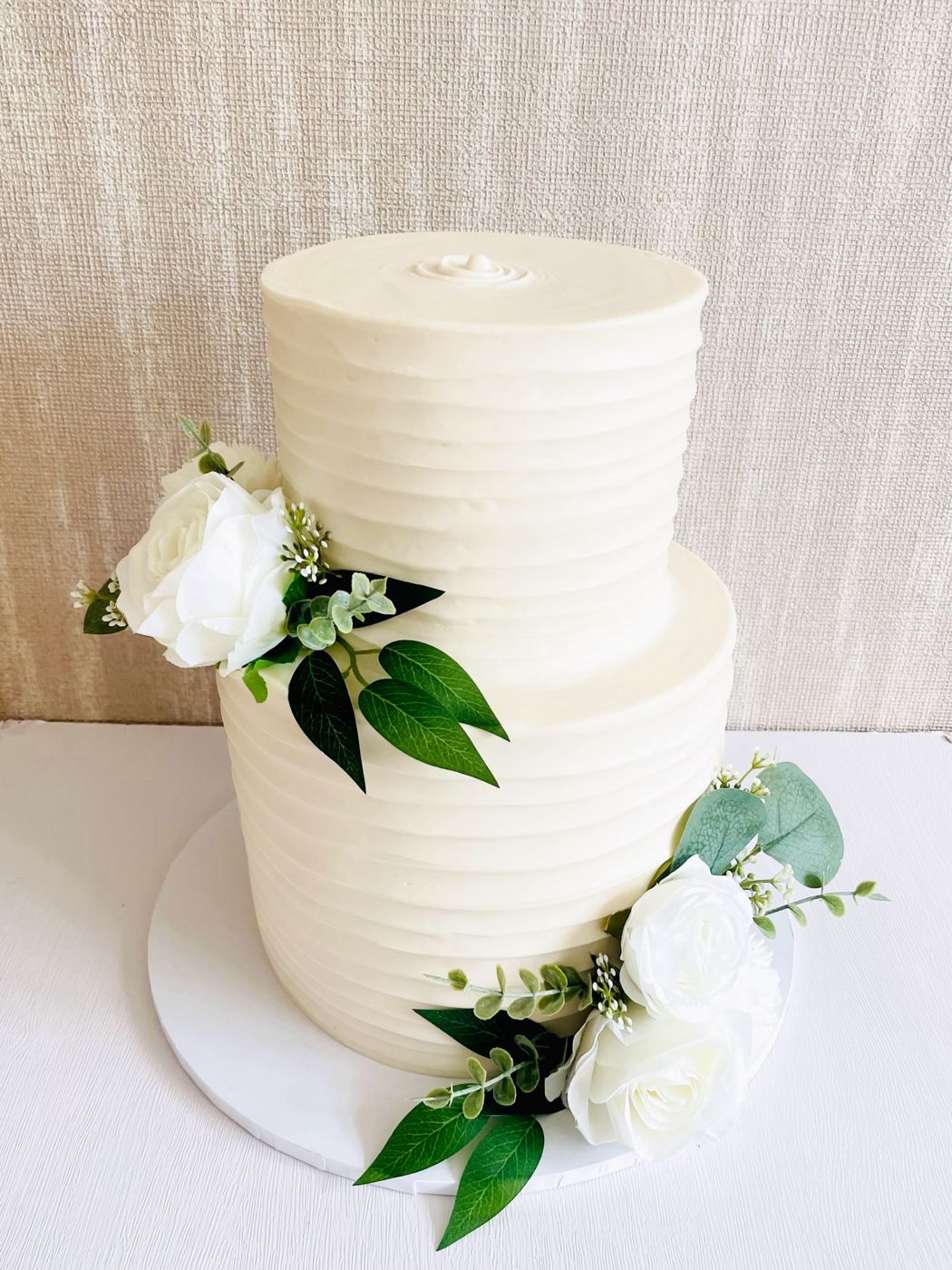 An elegant two-tier white wedding cake with fresh flowers